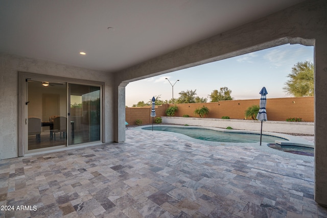 pool at dusk with a patio area