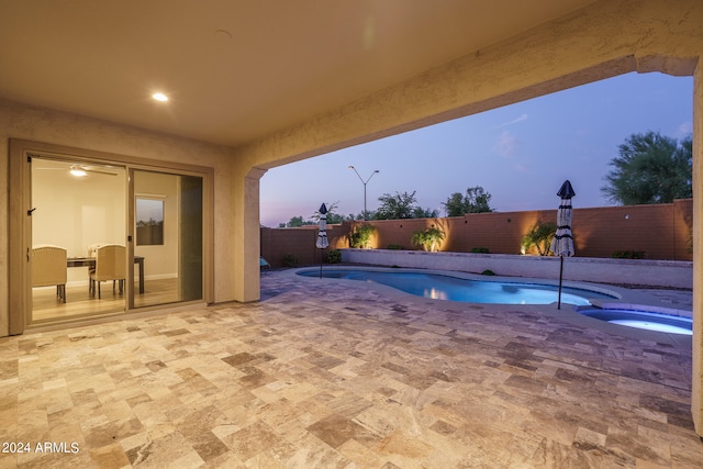 patio terrace at dusk with a fenced in pool