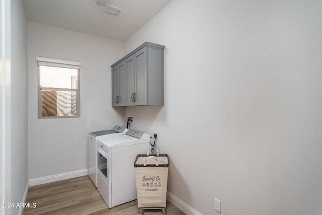 washroom featuring separate washer and dryer, light hardwood / wood-style floors, and cabinets