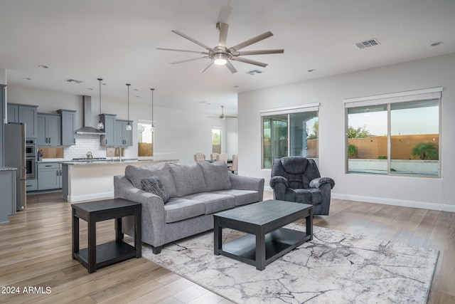 living room with plenty of natural light, light hardwood / wood-style flooring, and ceiling fan