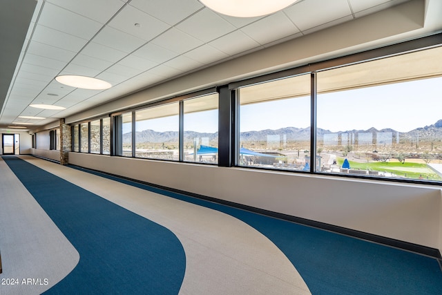 interior space with multiple windows, a mountain view, and a drop ceiling