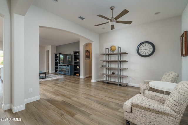 living area with a fireplace, light hardwood / wood-style flooring, and ceiling fan