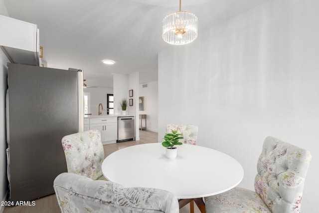 dining space with ceiling fan with notable chandelier, light wood-type flooring, and sink