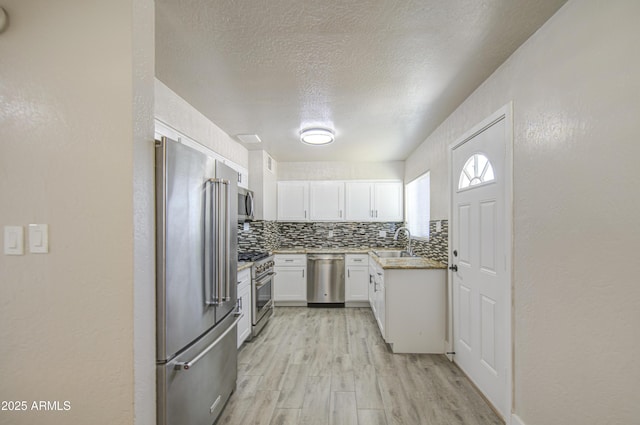 3408 W Virginia Ave, Phoenix, AZ 85009 - kitchen featuring high end appliances, a sink, light wood-type flooring, white cabinets, and tasteful backsplash