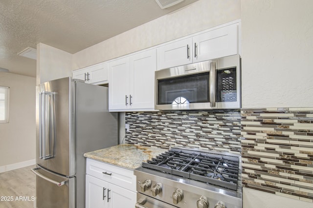3408 W Virginia Ave, Phoenix, AZ 85009 - kitchen with appliances with stainless steel finishes, tasteful backsplash, white cabinetry, light wood finished floors, and a textured ceiling