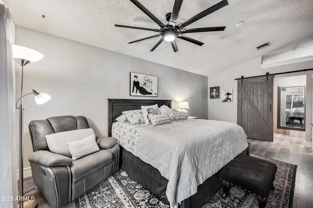 13207 N 55th Ave, Glendale, AZ 85304 - bedroom with vaulted ceiling, a barn door, a textured ceiling, wood finished floors, and a ceiling fan