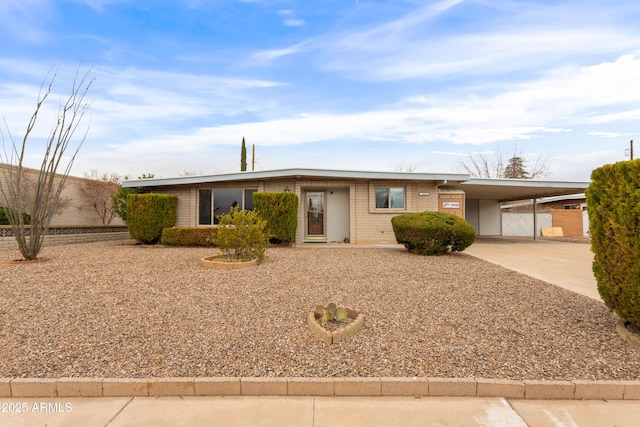 ranch-style home with an attached carport, concrete driveway, and brick siding