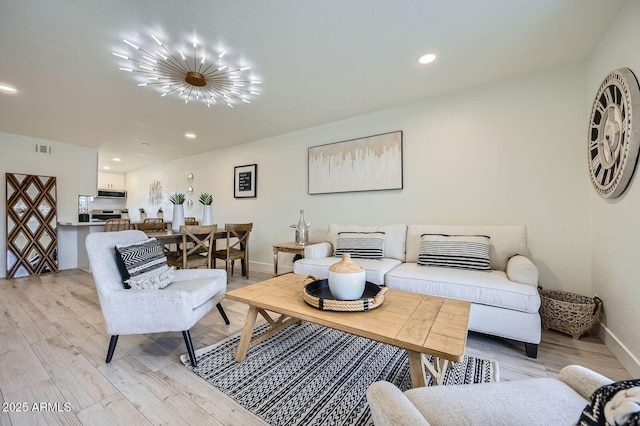 living room with visible vents, baseboards, light wood-style flooring, recessed lighting, and a notable chandelier