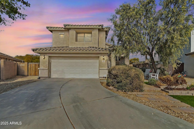 mediterranean / spanish house with a garage, fence, driveway, and stucco siding