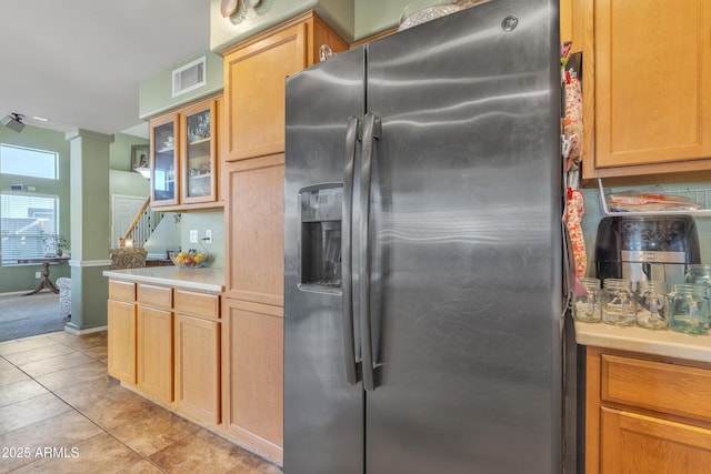 kitchen featuring light tile patterned floors, visible vents, light countertops, stainless steel refrigerator with ice dispenser, and glass insert cabinets