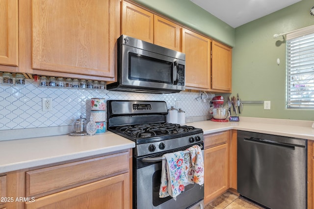 kitchen featuring light countertops, appliances with stainless steel finishes, light brown cabinetry, and decorative backsplash