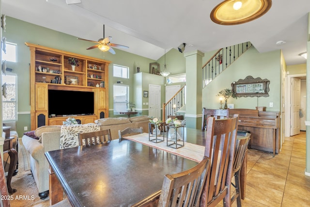 dining area with a ceiling fan, lofted ceiling, stairway, and light tile patterned floors