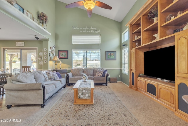 living area with ceiling fan, high vaulted ceiling, baseboards, and light colored carpet