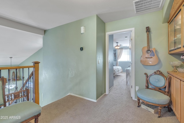 hall with baseboards, visible vents, and light colored carpet