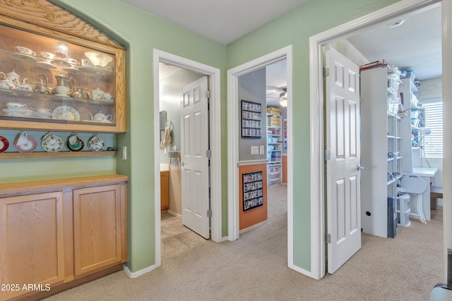 hall featuring light carpet and baseboards