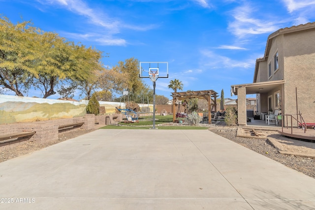 view of patio with basketball court, fence, and a pergola