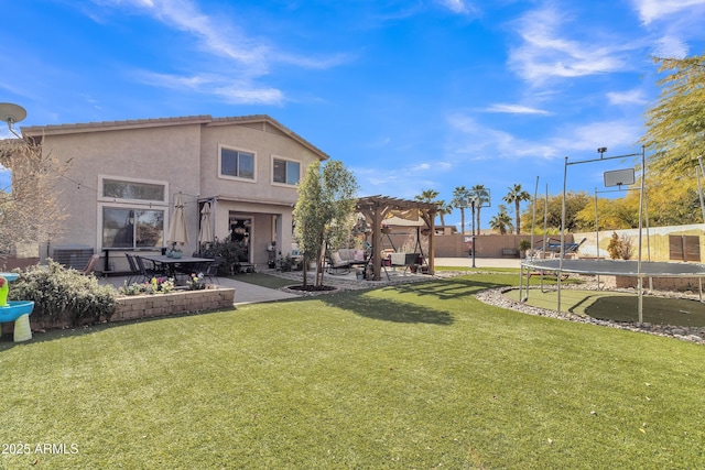 back of property featuring a pergola, fence, a lawn, stucco siding, and a trampoline