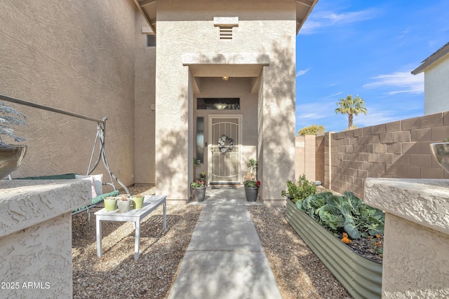 property entrance with fence and stucco siding