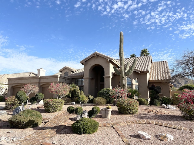 mediterranean / spanish house with a tiled roof, a garage, and stucco siding