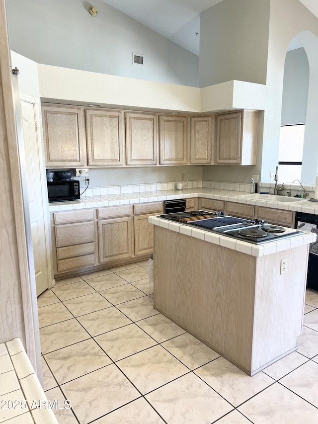 kitchen with visible vents, light brown cabinetry, tile countertops, light tile patterned floors, and a sink