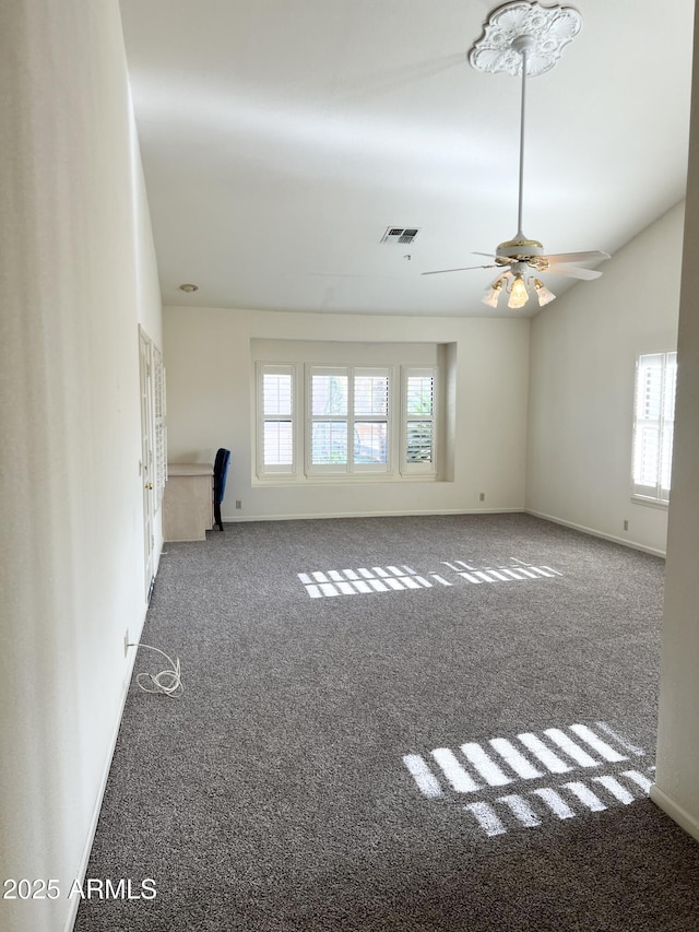 empty room featuring visible vents, carpet flooring, baseboards, and lofted ceiling