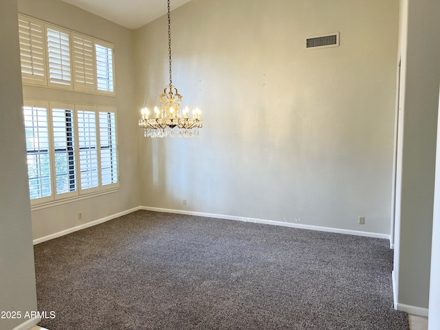 unfurnished room featuring baseboards, visible vents, an inviting chandelier, a towering ceiling, and dark colored carpet