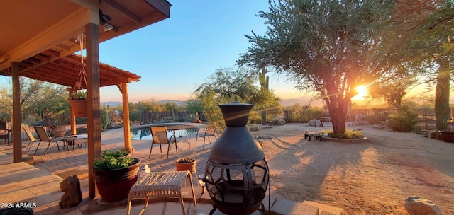 patio terrace at dusk featuring a fenced in pool