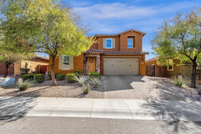 view of front of house with decorative driveway, a tile roof, stucco siding, fence, and a garage