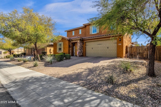 mediterranean / spanish-style house with a garage, fence, a tiled roof, decorative driveway, and stucco siding