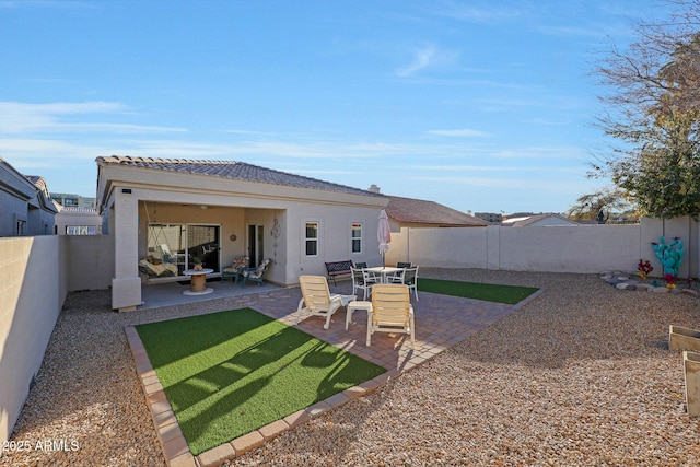 rear view of house featuring stucco siding, a fenced backyard, and a patio