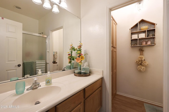 bathroom with an enclosed shower, vanity, wood finished floors, a chandelier, and baseboards