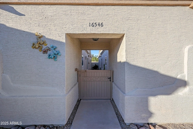 doorway to property featuring a gate and stucco siding