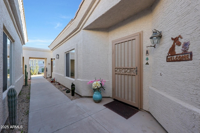 view of exterior entry featuring a patio area and stucco siding