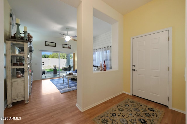 foyer with a ceiling fan, baseboards, and wood finished floors