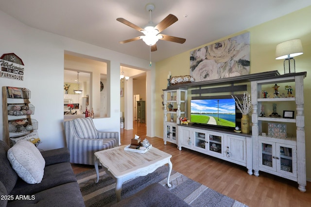 living room featuring wood finished floors and ceiling fan with notable chandelier