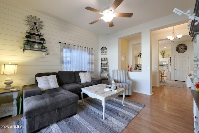 living room featuring ceiling fan with notable chandelier and wood finished floors