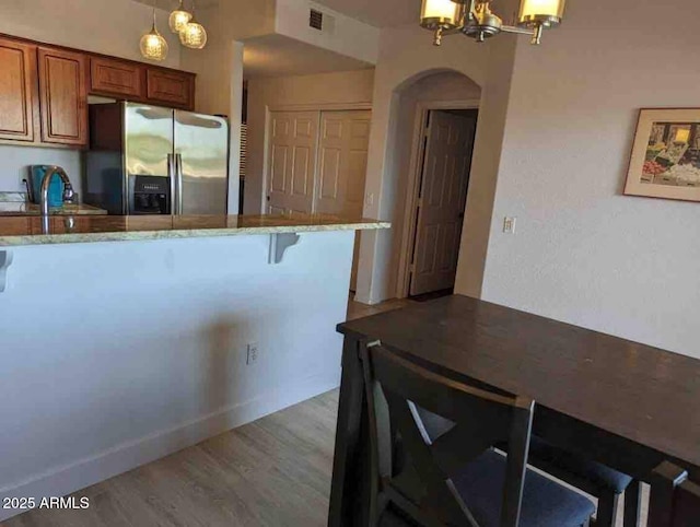 920 E Devonshire Ave Unit 2031, Phoenix, AZ 85014 - kitchen with stainless steel refrigerator with ice dispenser, a chandelier, brown cabinetry, light stone countertops, and light wood finished floors