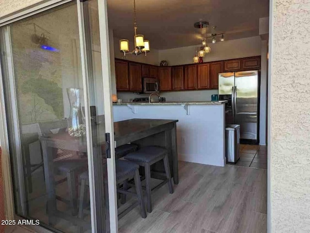 920 E Devonshire Ave Unit 2031, Phoenix, AZ 85014 - kitchen featuring appliances with stainless steel finishes, a breakfast bar area, a chandelier, hanging light fixtures, and light wood-style floors