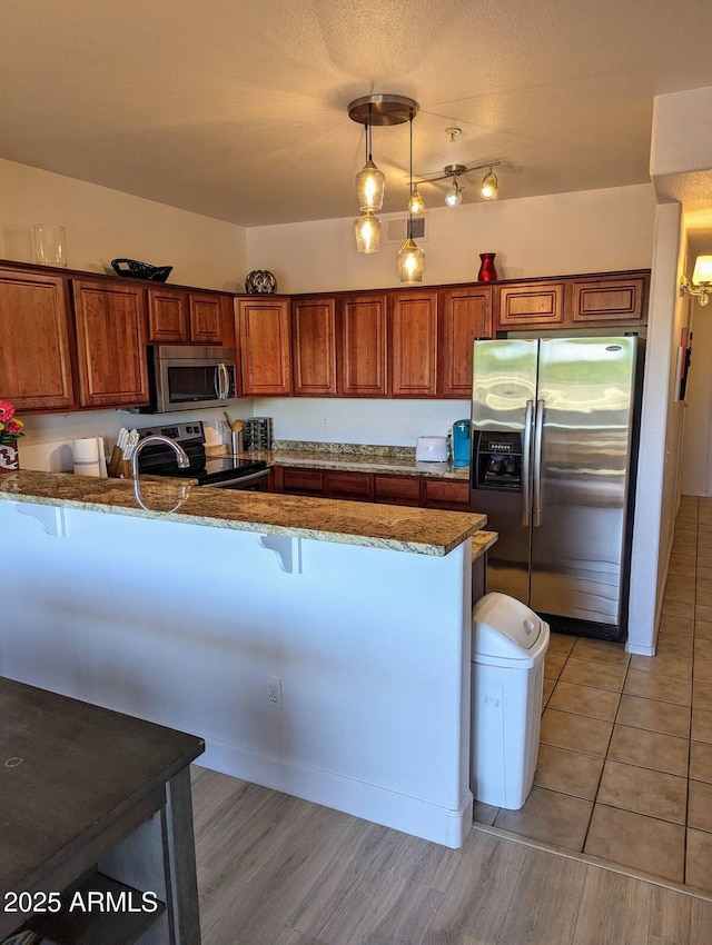 920 E Devonshire Ave Unit 2031, Phoenix, AZ 85014 - kitchen with appliances with stainless steel finishes, dark stone counters, brown cabinets, a kitchen breakfast bar, and a peninsula