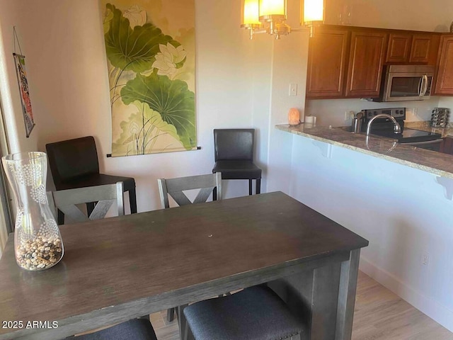 920 E Devonshire Ave Unit 2031, Phoenix, AZ 85014 - kitchen with stainless steel appliances, brown cabinets, stone counters, light wood-type flooring, and a chandelier