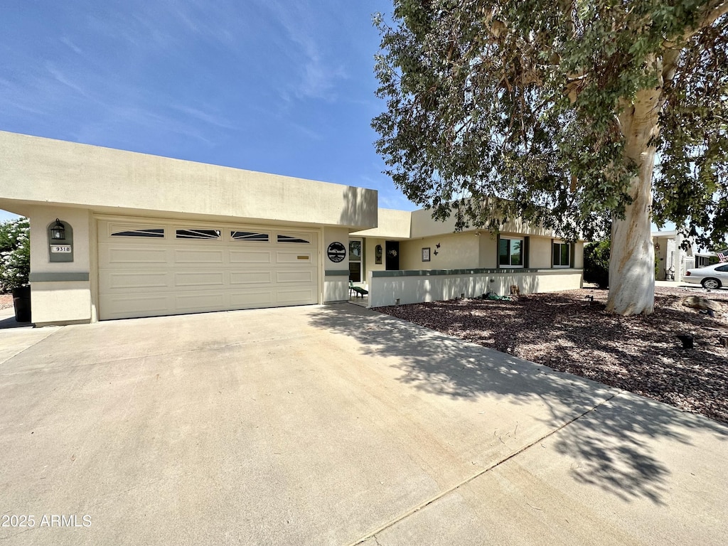 9318 W Briarwood Cir, Sun City, AZ 85351 - pueblo-style home with concrete driveway, stucco siding, and an attached garage
