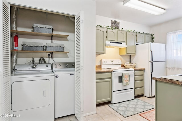 kitchen featuring light tile patterned floors, light countertops, under cabinet range hood, washer and dryer, and white appliances