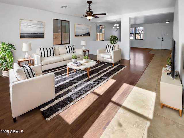 living room with ceiling fan with notable chandelier and hardwood / wood-style flooring