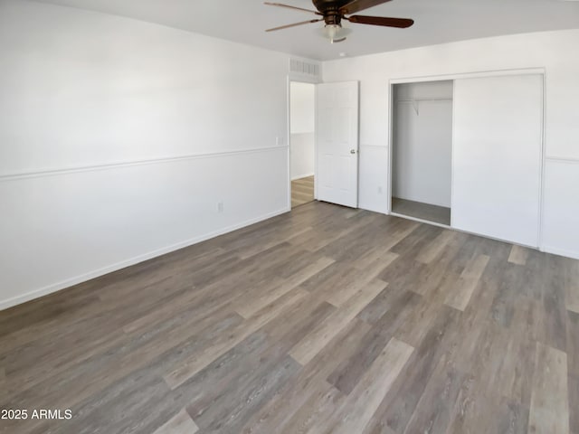 unfurnished bedroom featuring dark wood-type flooring, ceiling fan, and a closet