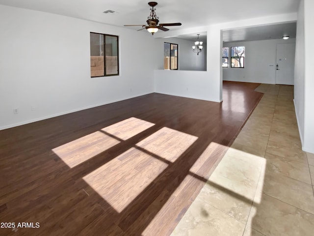 empty room featuring ceiling fan with notable chandelier and wood-type flooring