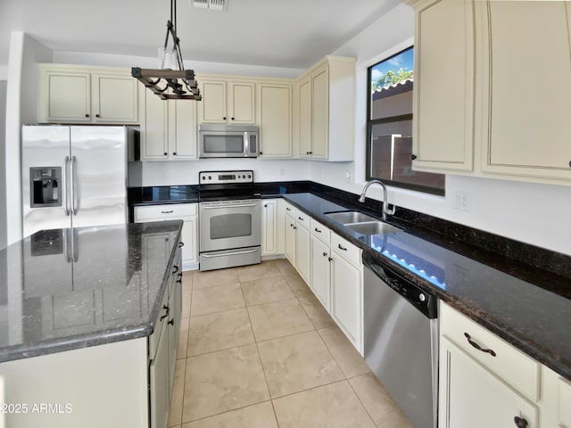 kitchen with stainless steel appliances, sink, dark stone countertops, light tile patterned floors, and hanging light fixtures