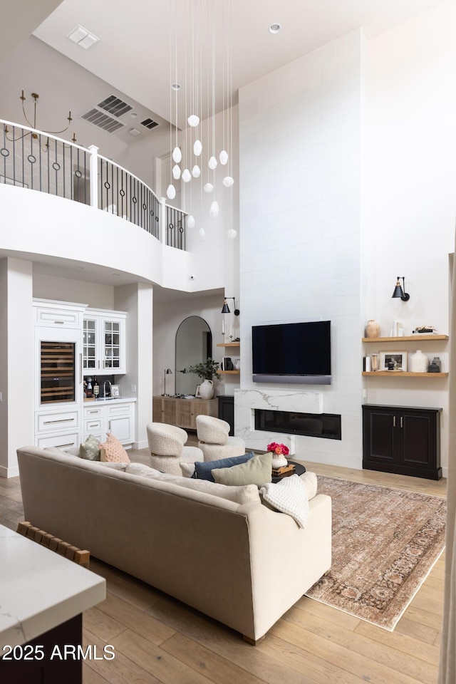 living area featuring a high ceiling, light wood-type flooring, and a fireplace
