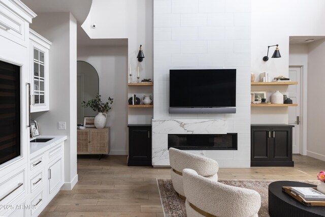 living area featuring a fireplace, light wood-style flooring, and baseboards