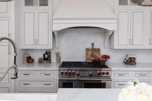 kitchen with double oven range, decorative backsplash, and white cabinets