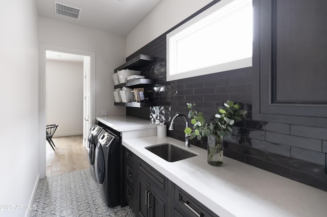 kitchen featuring washing machine and dryer, a sink, open shelves, backsplash, and light countertops